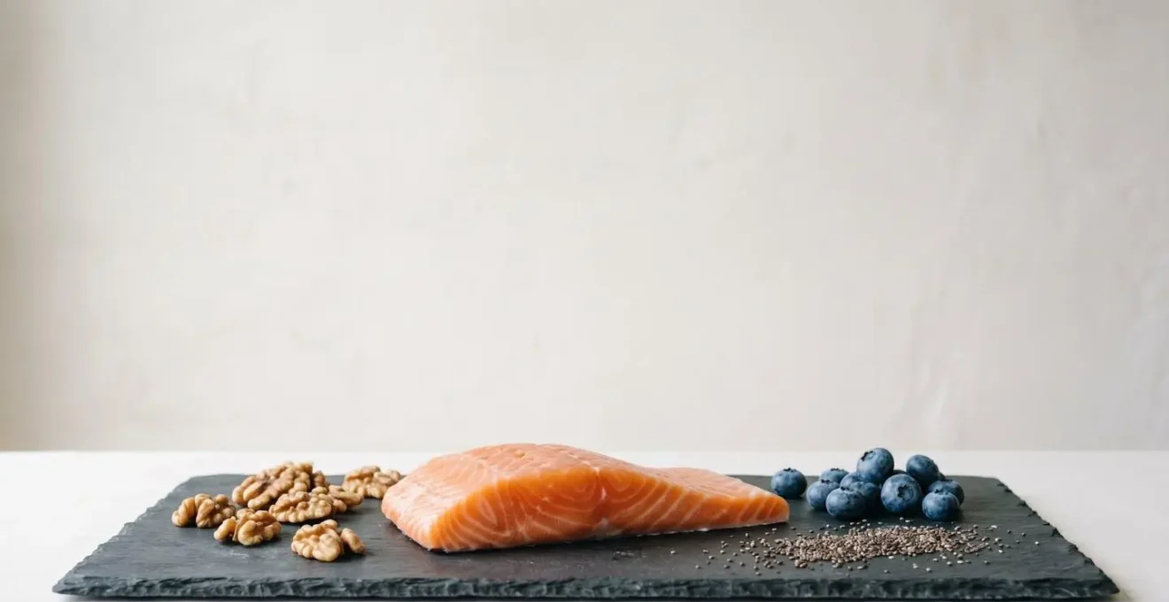 A minimalist composition with a salmon fillet, walnuts, and blueberries on a slate surface, symbolizing brain health and neuroplasticity.