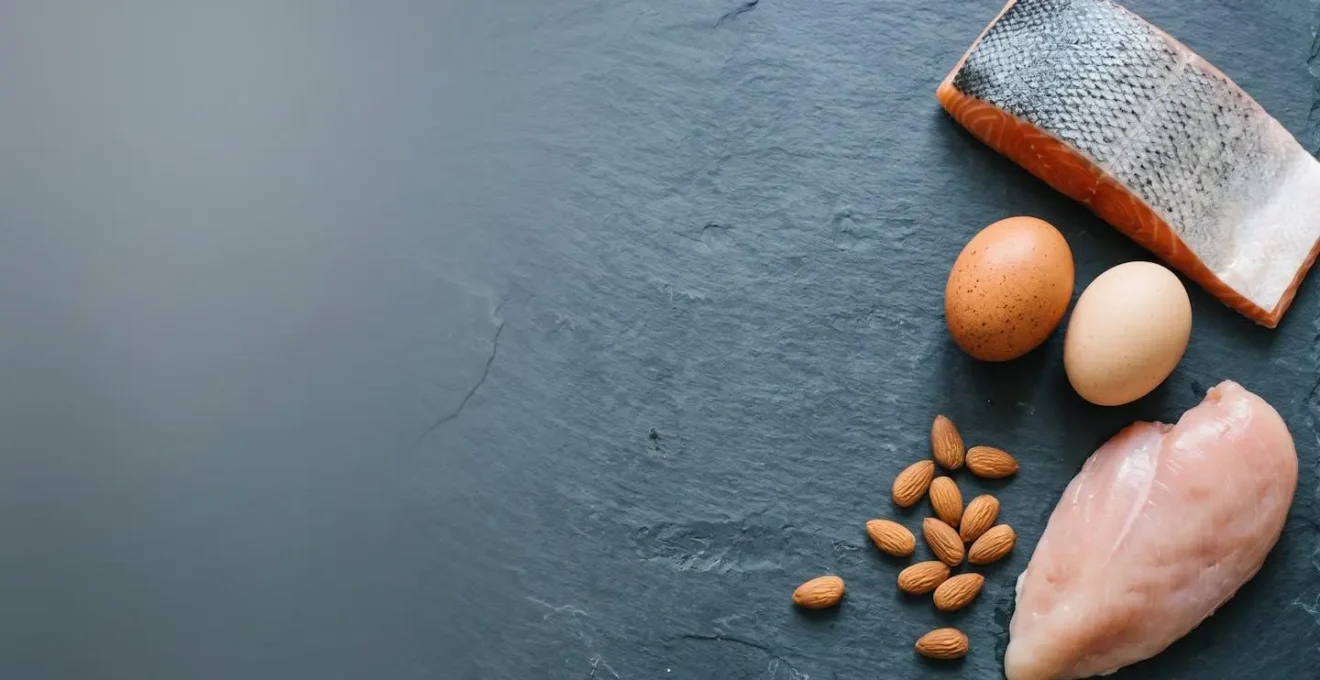 Minimalist overhead view of whole protein foods arranged on natural stone surface with soft natural lighting